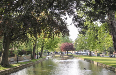 Charming Bourton-on-the-Water village with picturesque River Windrush flowing through, stone bridges and quaint cottages.