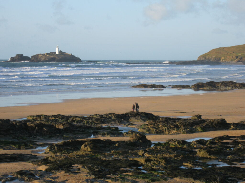 Godrevy Beach with a breathtaking view of the blue sky, adorned with a majestic Lighthouse on an island.