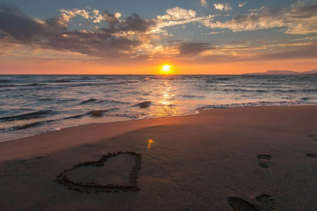 A heart drawn on sandy beach of Hayle Cornwall at sunset, symbolizing love and romance in a serene setting.