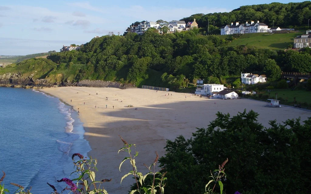 Porthminster Beach in St Ives which is surrounded by mountain and on which their is shadow of trees. Beaches in St Ives
