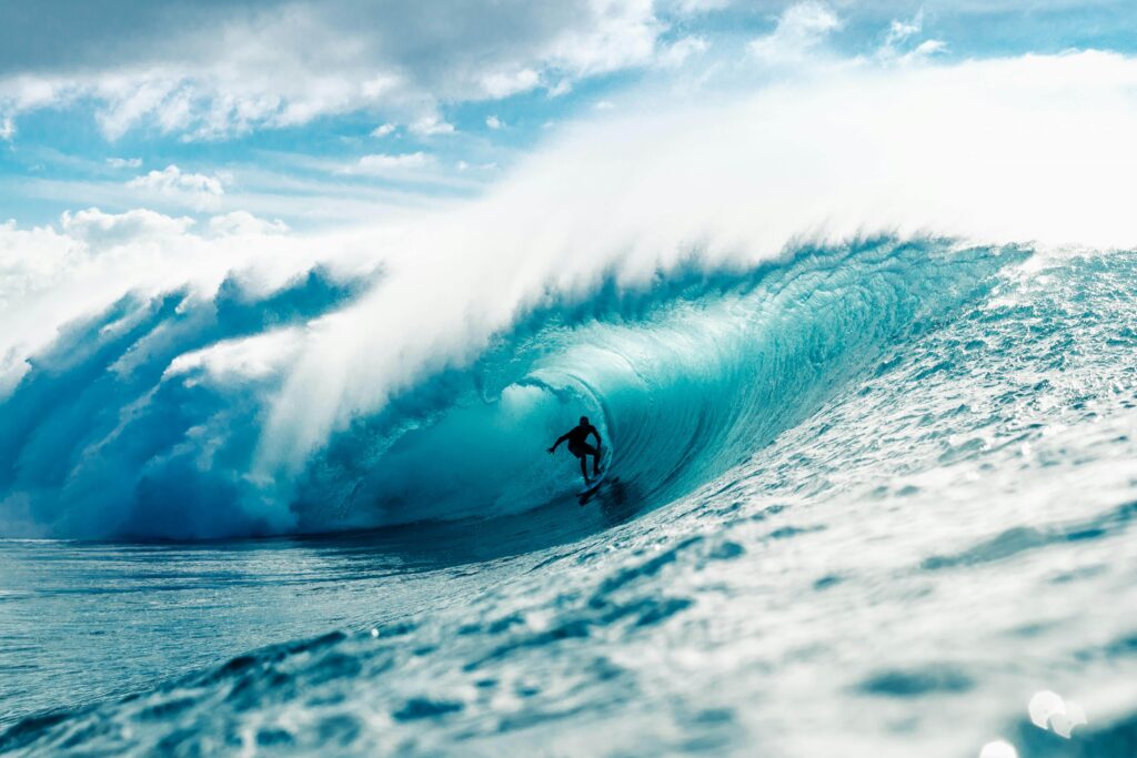 A surfer skillfully rides a massive ocean wave in th Atlantic Ocean near the beaches of Hayle in Cornwall, displaying balance and control amidst the powerful waters.