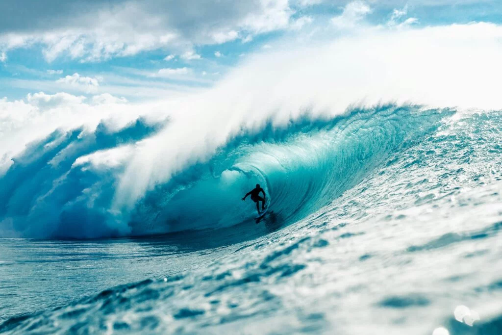 A surfer skillfully rides a massive ocean wave in th Atlantic Ocean near the beaches of Hayle in Cornwall, displaying balance and control amidst the powerful waters.