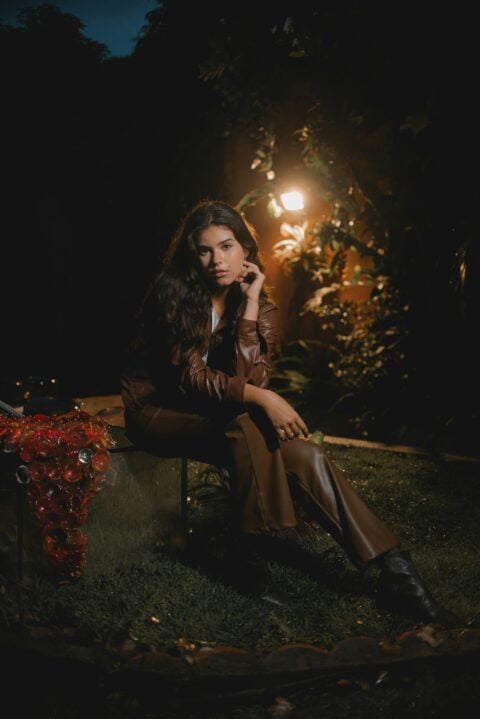 A Girl in brown leather pants and boots sitting on a bench in the darkness. Are leather pants business casual?