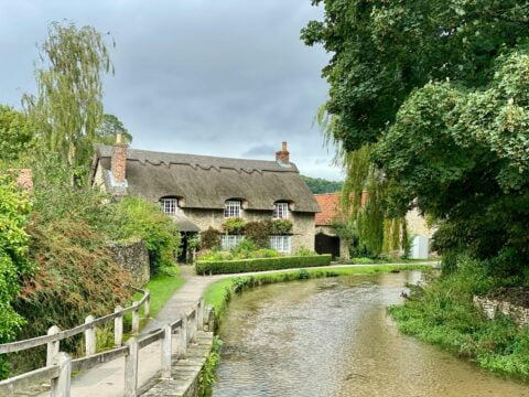 Thatched roof house in Bourton on the Water with river windrush passing through.