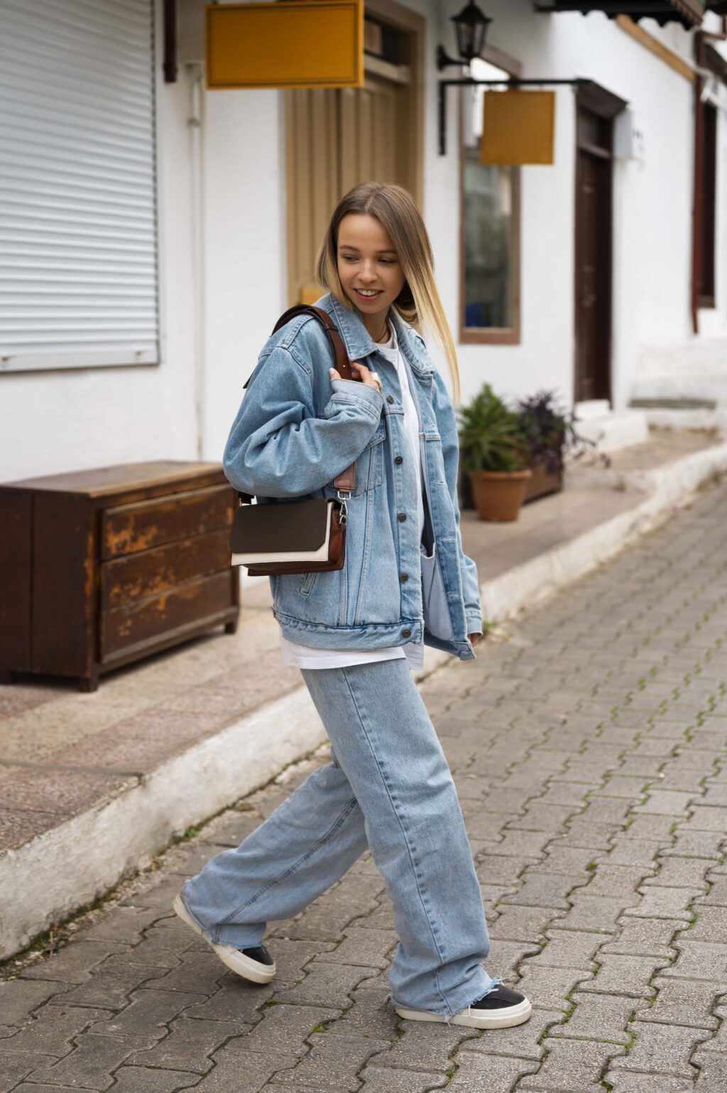 A stylish woman in a denim jacket and High-Waisted Wide-Leg Jeans strutting confidently down the street.