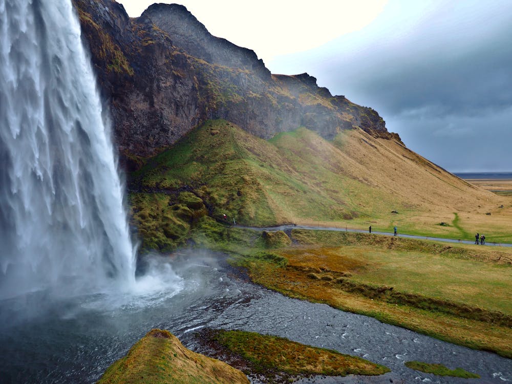A serene early morning visit to Seljalandsfoss in Iceland, featuring the waterfall flowing over a rocky cliff and mist rising from the water below.