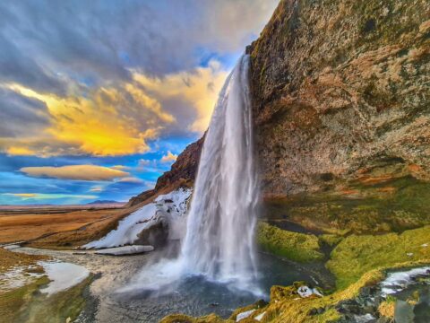 Scenic view of a Seljalandsfoss waterfall in Iceland, with a dramatic mountainous landscape.