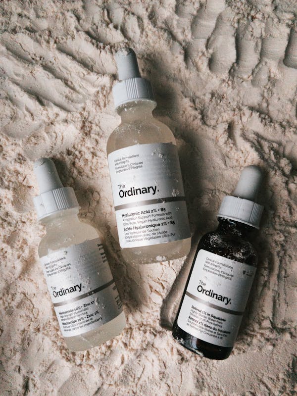 Various skincare products on white surface, including Hyaluronic Acid serum and moisturizer.