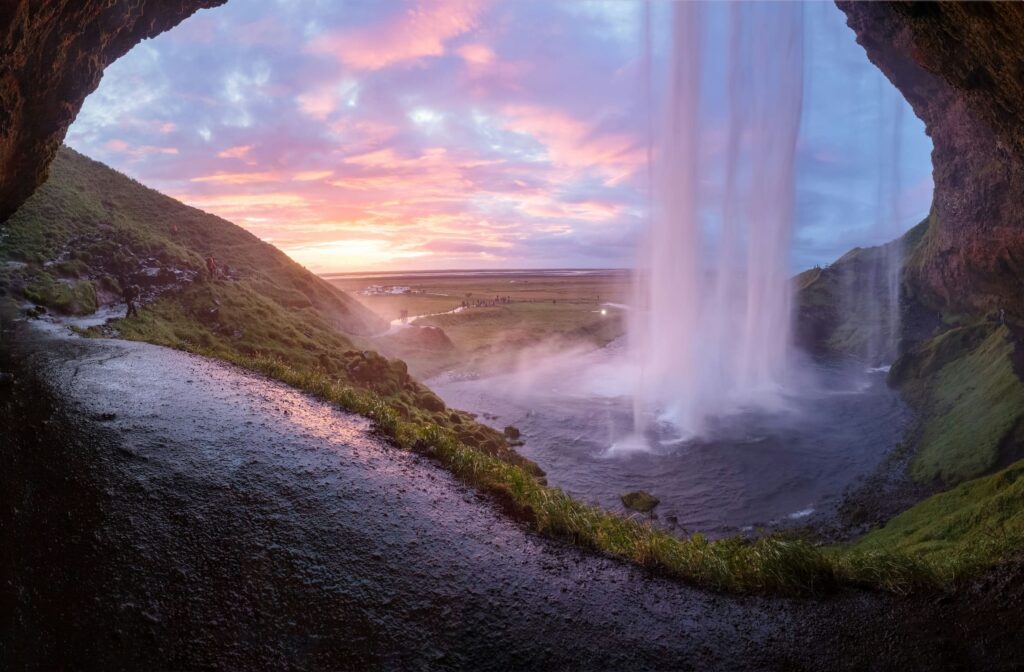Majestic Seljalandsfoss waterfall Iceland, surrounded by lush greenery and towering mountains.