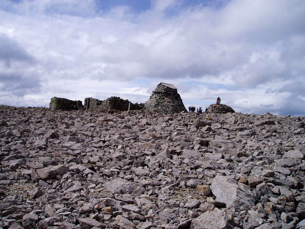 A rocky landscape at Ben Nevis Observatory with a few people standing atop, enjoying the breathtaking mountain views.