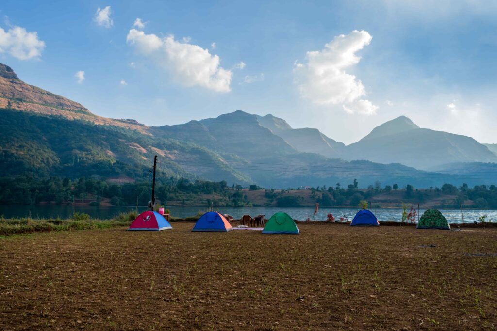 A scenic view of Dolgam Campsite in Snowdonia National Park, featuring tents set up in a field by a tranquil lake.