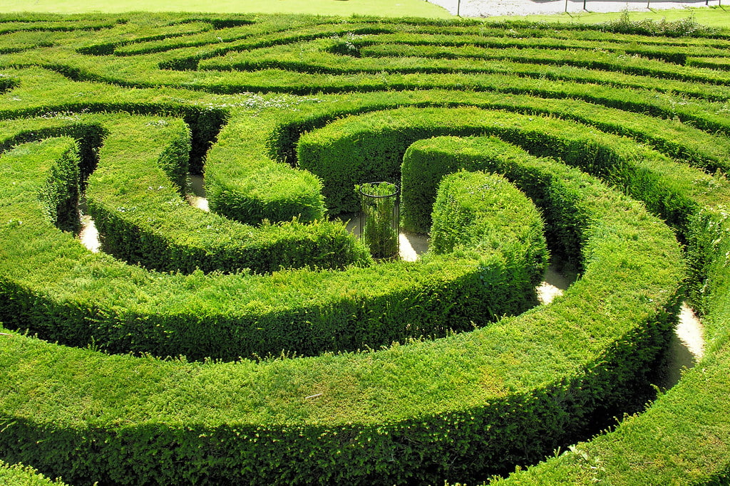 The Dragon Fly Maze in Bourton-on-the-Water, intricately designed, sits in a vibrant green field, inviting exploration.