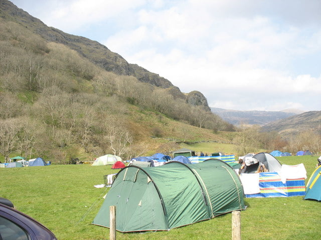 Llyn Gwynant campsite in Snowdonia National Park, featuring tents pitched on a grassy field with stunning mountain views.