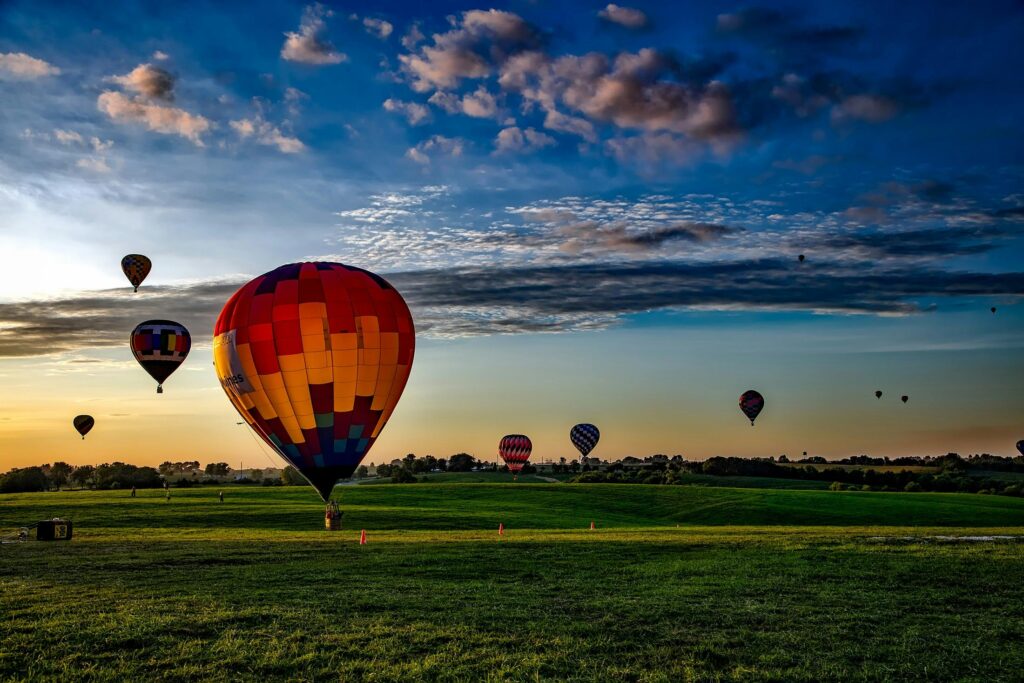 Colorful hot air balloons soar high in the sky over Bourton-on-the-Water, creating a stunning aerial spectacle.