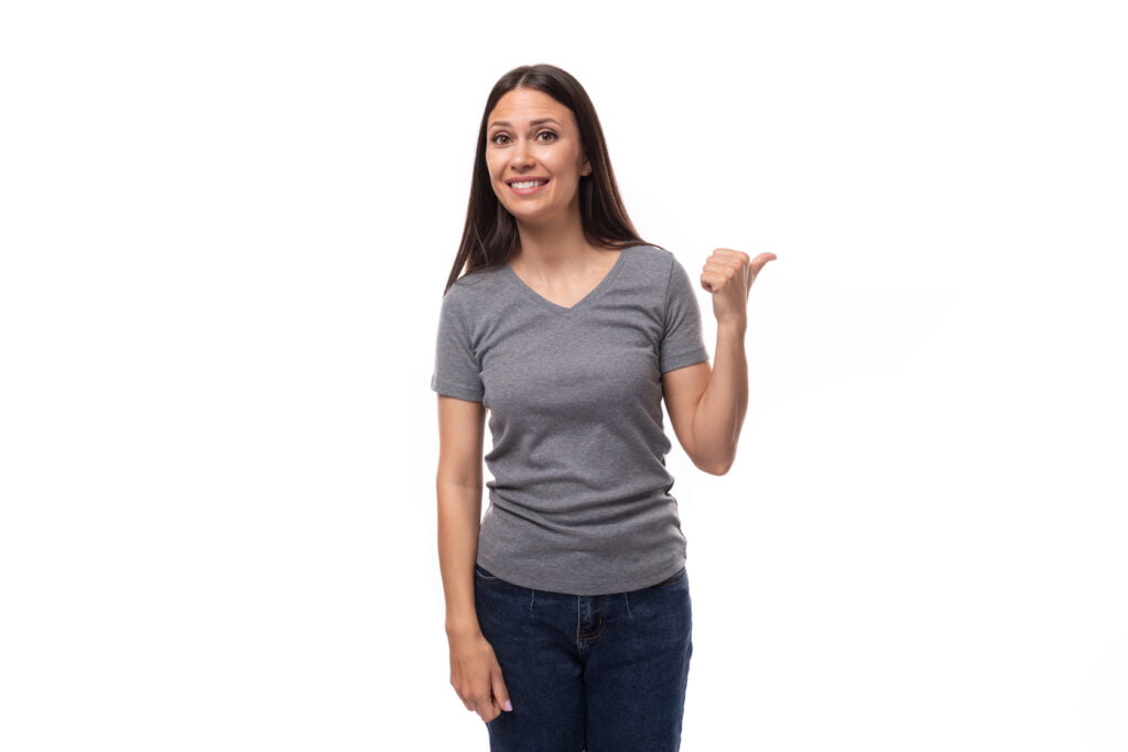A woman in a gray V-neck shirt points at something, showcasing her engagement and curiosity in the moment.