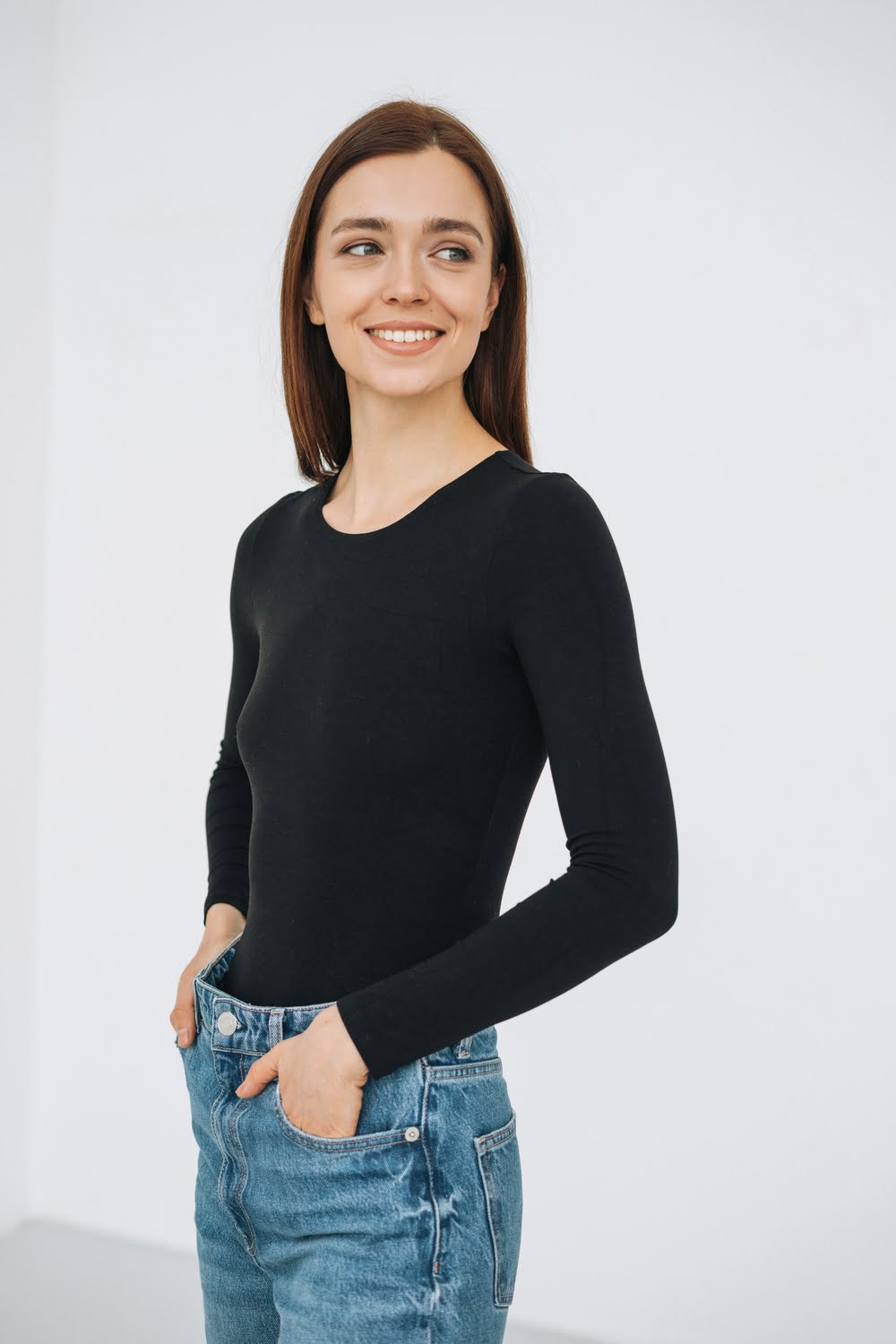 Smiling woman wearing a black Zara Minimal Long Sleeve top and jeans, radiating confidence and style.
