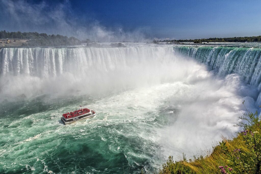 Captivating scene of Niagara Falls, Canada, featuring the iconic waterfalls and a boat from Niagara City Cruises in the foreground.