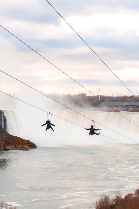 An exciting view of people zip lining over the stunning Niagara Falls, experiencing the rush of nature's power from above.