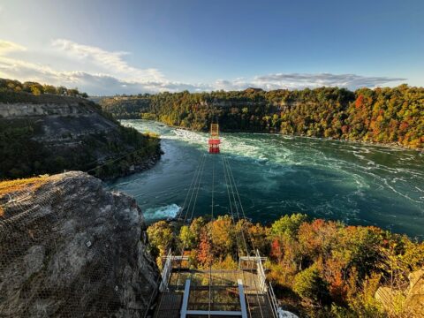 Stunning aerial perspective of Niagara Falls from a cliff, featuring the Whirlpool Aero Car soaring over the cascading waters.