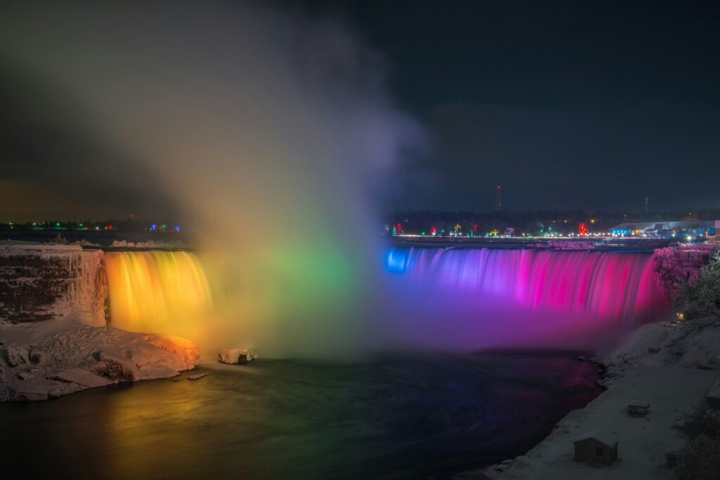 A stunning view of Niagara Falls illuminated at night, showcasing the cascading water and vibrant lights reflecting on the surface.