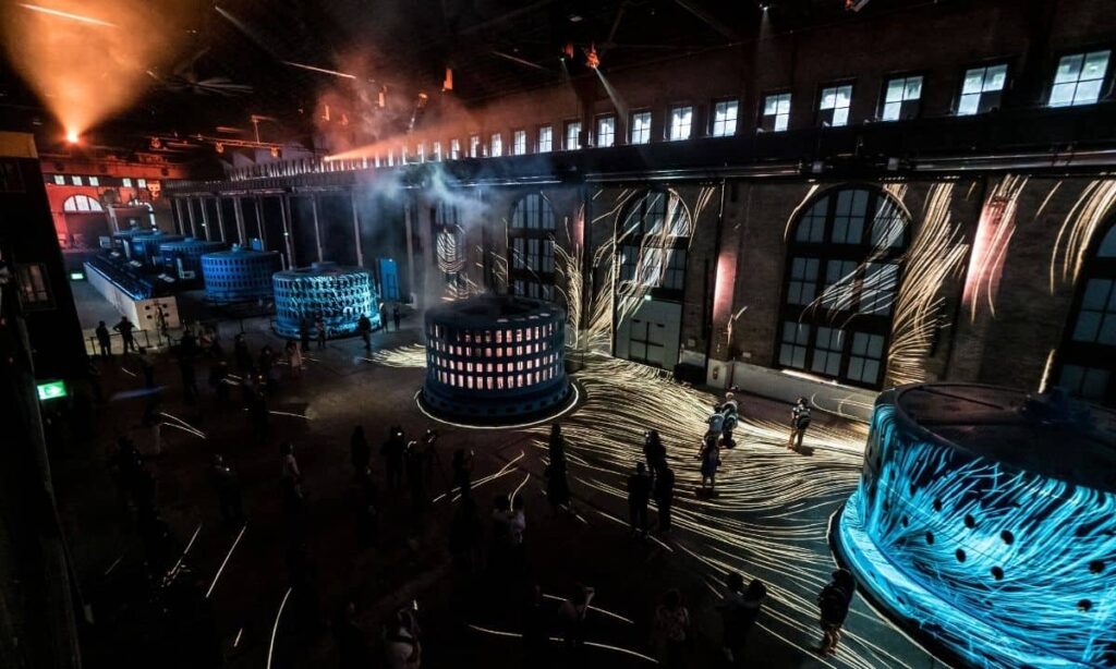 Generator Hall at Niagara Parks Power Station at night, filled with people and illuminated by soft, ambient lights.